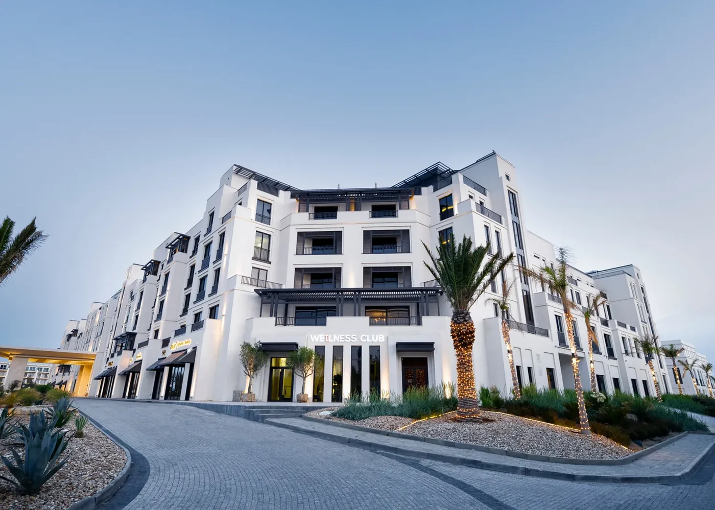 The Grand-ın axşam fasadı: girişin üstündə Wellness Club lövhəsi