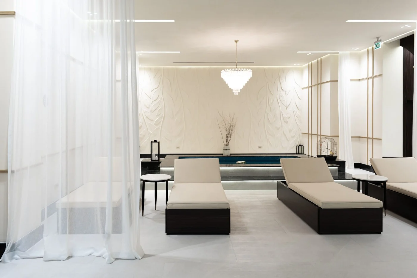 A white relaxation zone: a curtain, sunloungers, a plunge pool and a chandelier